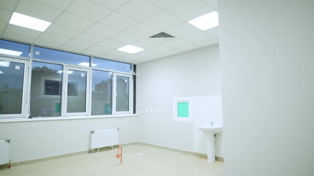 Empty medical laboratory features white walls ceiling lamps sink and windows. Clean interior creates sterile atmosphere in hospital ward