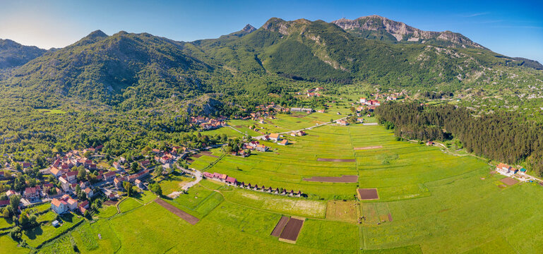 Njegusi village nestled in a green mountain valley, surrounded by lush forests and towering peaks, offering a scenic panorama of Lovcen National Park