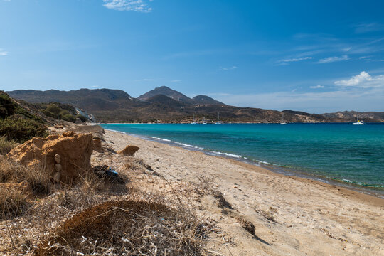 Sandy path above a turquoise bay on Milos island with rocky hills