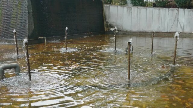 Industrial wastewater treatment facility with bubbling aeration pipes in a concrete basin.