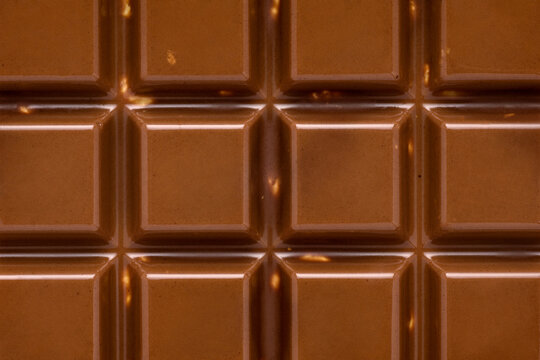 Milk chocolate bar close up showing square texture.