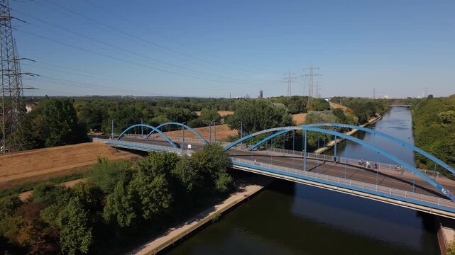 Aerial Video Approaching Blue Arch Bridge Crossing River with Surrounding Forest in Karnap