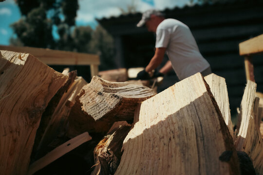 Man stacking chopped firewood into wooden crate outdoors in backyard