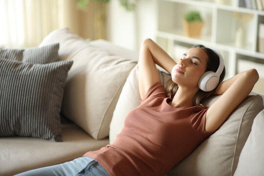 Woman wearing headphones is relaxing sitting on a couch