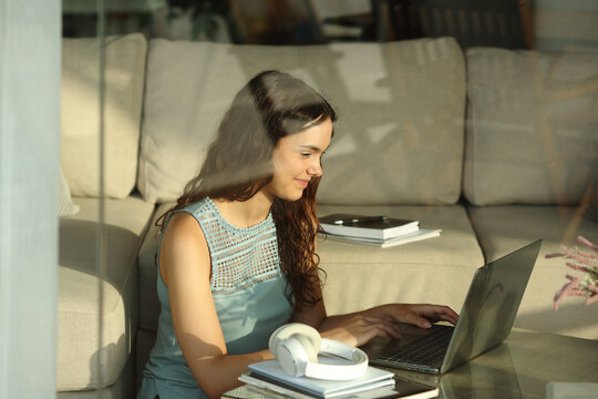 Satisfied student typing on computer at home