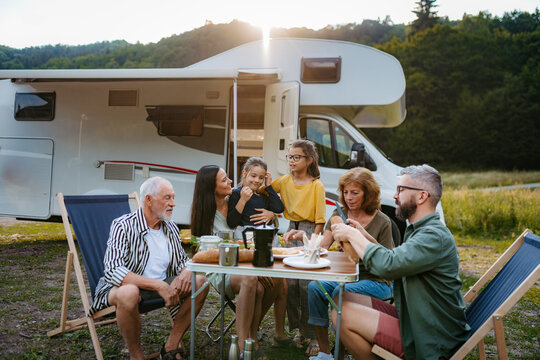 Multigenerational family having picnic dinner during summer caravan vacation.