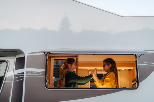 Two sisters playing inside camper during family summer vacation.