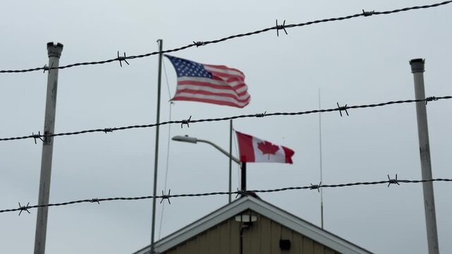 US flag and flag of Canada are waving against the sky and barbed wire. Border. Checkpoint. Trade war. USA VS Canada.