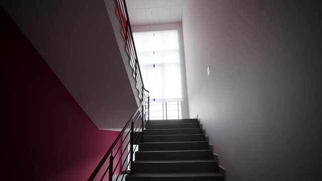Interior staircase features dark steps and minimalist metal railings. Light pink walls surround stairs creating clean modern environment