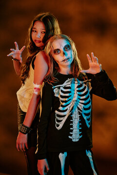Portrait of diverse children wearing Halloween costumes and spooky makeup posing back to back. Image suitable for seasonal marketing campaigns and holiday event promotions, vertical