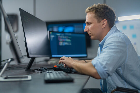 DevOps engineer, Caucasian male programmer working on computer monitors in modern IT office, software operations, system deployment, cloud infrastructure and advanced technology business innovation