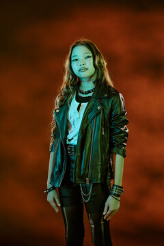 Portrait of Asian teenager girl wearing spooky Halloween makeup and leather jacket looking at camera. Image suitable for seasonal marketing campaigns and youth event promotions, vertical
