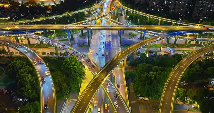 Illuminated multilayer highway interchange carries nighttime traffic through a green urban district, highlighting modern transport infrastructure and city connectivity.