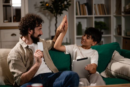 Father and son high-fiving for successful online purchase