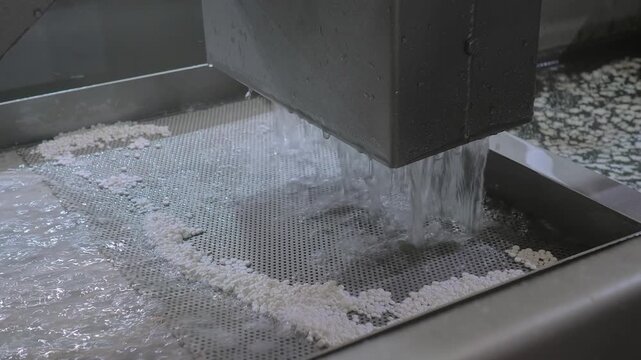 Close up: fast water flow with recycled plastic granules, pellets for filtration, separation the plastic material - plastic pelletizer recycling machine. Reuse, waste reduction and sustainable concept