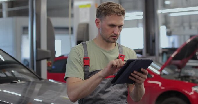 Portrait of a skilled car mechanic in a workshop, with service in the background.
