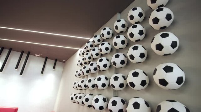 Creative art installation composed of classic black and white soccer balls on wall. Dynamic geometry brings sport spirit to visitors