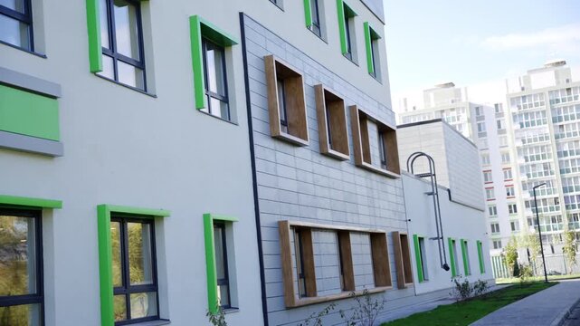 Renovated educational building displays fresh colorful exterior wall panels on daytime. Sunny clear sky creates optimistic pleasant mood