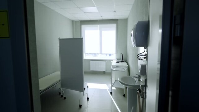 Doctor office features mobile partition screen sink and workstation computer. Organized layout presents comfortable treatment room