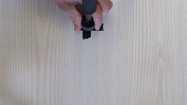 Closeup hand aligning tape marker on light wood table, placing small stand base onto crossshaped electrical tape marker, steady motion, studio prep for microphone mount