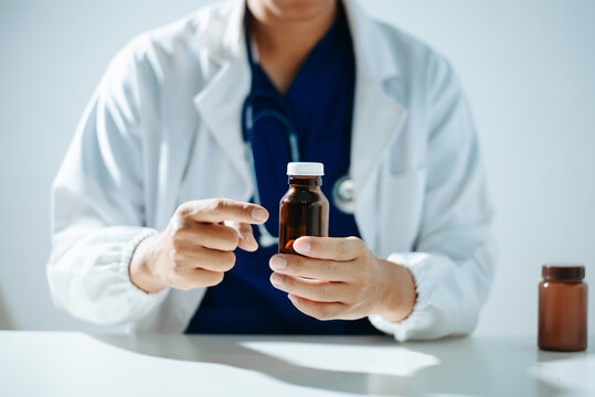 A professional scientist in a lab coat inspecting blue and white medical capsules on a petri dish. Concept of pharmaceutical research, health care development