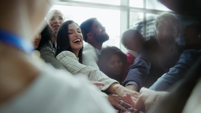 A group of happy professionals gathers, hands together, symbolizing teamwork, unity, and shared success. Their cheerful expressions convey accomplishment and strong collaboration.