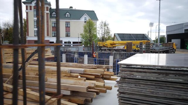 Multi story residential building stands under cloudy sky. Foundation works involve metal reinforcement cages concrete formwork panels