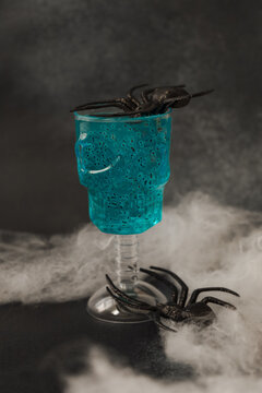 Halloween drink with blue liquid and fake spiders on skull cup