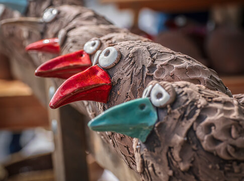 Handmade Ceramic Bird Sculptures With Colorful Beaks on a Rustic Wooden Shelf
