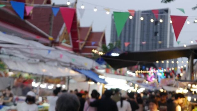 Blurred Crowd at Thai Night Market with Bokeh String Lights and Colorful Flags