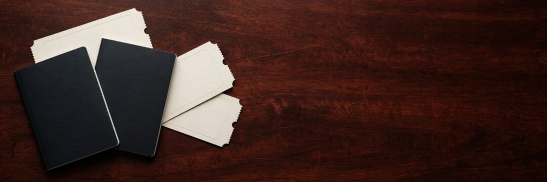 Two black notebooks and white envelopes on a dark wooden table.