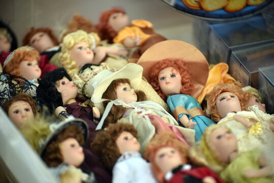 Collection of small retro dolls lying among vintage objects at a flea market, creating a nostalgic scene filled with childhood memories and collectible toys.
