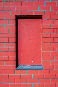 Single Boarded Window Disappears Into a Vivid Red Brick Facade