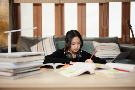 One Asian teenage girl concentrates on learning at home, reading textbooks, note writing, self-tutorial exams, preparation for back to school, Homeschooling, university knowledge education lifestyle.