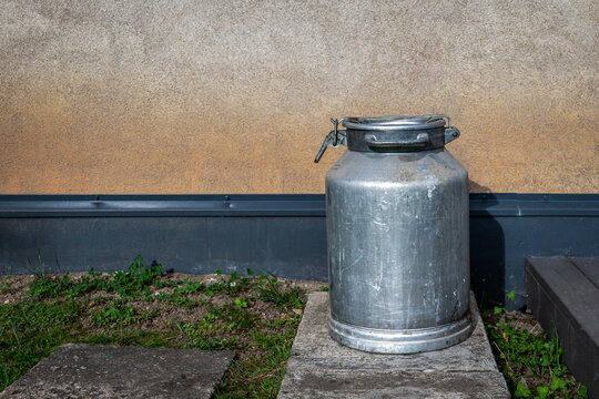 Vintage Aluminum Milk Can Outside Rustic Farm Building with Copy Space