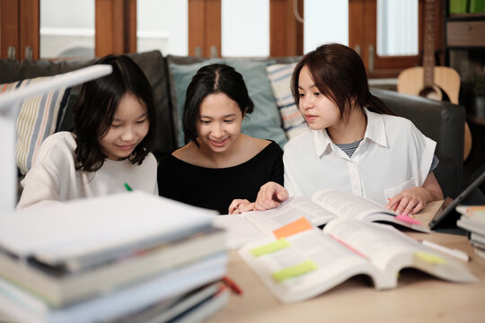 Three Asian teenage girls learning tutorials at home together, reading textbooks, writing notes, self-tutorial exams, preparing school homework, Homeschooling study, knowledge education lifestyle.