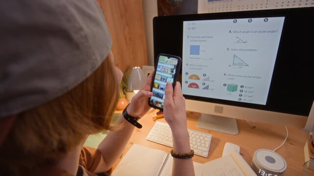 Caucasian teenager scrolling on smartphone instead of studying math on computer screen. Clip is suitable for educational apps, parenting blogs, or digital detox advertising