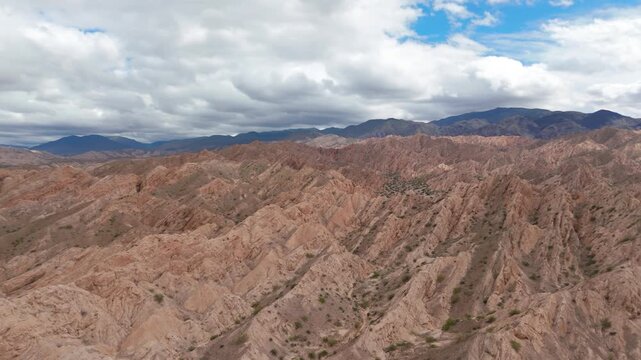 Expansive Quebrada de las Flechas mountain ridges under dramatic cloudy sky, aerial orbit left to right