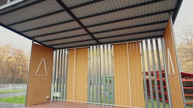Contemporary outdoor pavilion features wooden floors along with slatted walls. Quiet venue waits for performance and public event