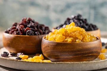 Golden raisin with black and dark red raisin assortment in wooden bowls as a healthy dried fruit snack on rustic table © Svetlana Kolpakova