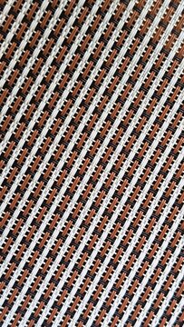 Close-up of a woven surface featuring a repeating diagonal pattern of white, brown, and black, creating a detailed decorative texture