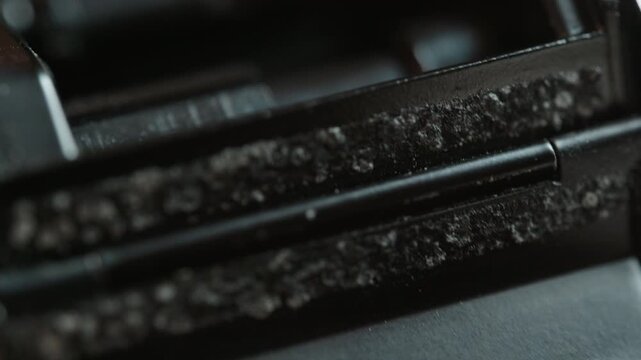 Macro shot: the vintage 35mm camera is repositioned, then a tool scrapes crumbled old light seals from the film channel, foam debris breaking away. Detailed restoration of analog gear before renewal.