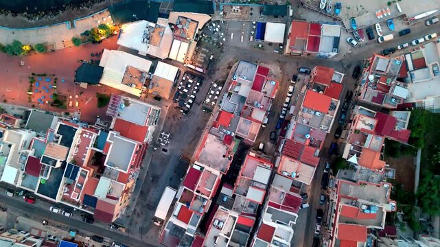 Top-down sunrise aerial of Sferracavallo village in Palermo, Sicily. Captures the waking port and residential rooftops from above.