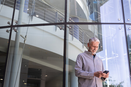 Senior Man Smiling While Using Cell Phone outdoors