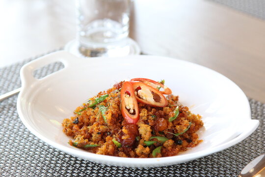Thai style crispy catfish stir-fried with red curry paste, salted egg yolks, and kaffir lime leaves in a white plate.