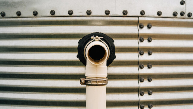 Pipe connected to water tank for irrigation in agricultural setting