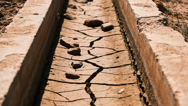 Dried up irrigation channel shows the effects of water scarcity on agriculture and soil moisture