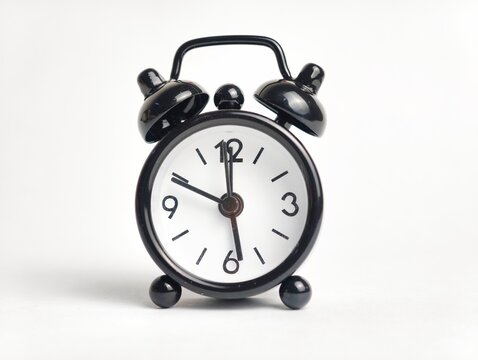Front view of a classic black mini twin bell alarm clock isolated on a plain white background.