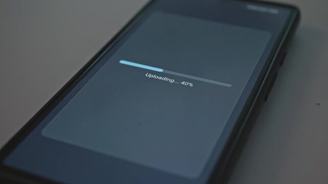 Close up of smartphone screen with file upload percentage bar finishing successfully concept for digital file transfer and data security
