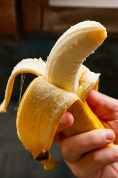 Man hand holding a peeled banana as a phallic symbol representing erectile dysfunction and men health. Metaphor for male potency, sexual performance and urology disease concept.